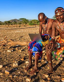 African warrior from Samburu tribe using laptop on savanna, central Kenya, Africa. Samburu tribe is one of the biggest tribes of north-central Kenya, and they are related to the Maasai.